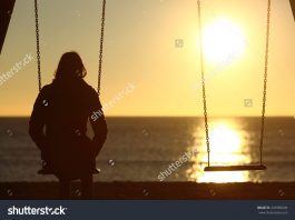 stock photo lonely woman watching sunset alone in winter on the beach at sunset