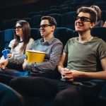 People with popcorn watching movie in cinema