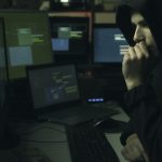 Hacker hiding in the dark and working with computers