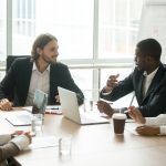 Business executives discussing project ideas at team meeting conference table