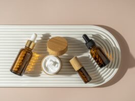 A face or hair serum or essential oil in a brown dropper bottle lying on a white ceramic plate