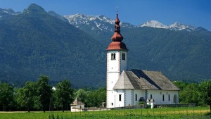 AJ3XN4 The church at Bitjne near lake Bohinj stands out in stark beauty against the surrounding mountains. Image shot 2006. Exact date unknown.