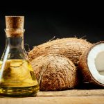 coconuts and a bottle of oil on a wooden table on a black background