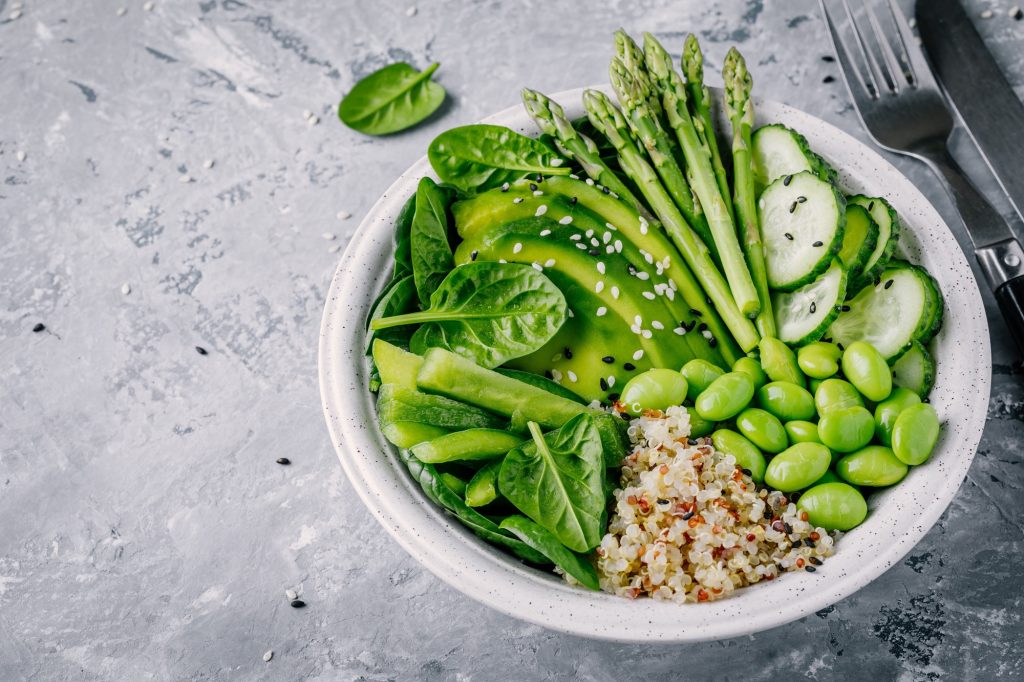 Green vegetarian bowl salad with quinoa, spinach, avocado, asparagus, cucumber, edamame