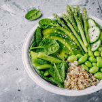 Green vegetarian bowl salad with quinoa, spinach, avocado, asparagus, cucumber, edamame