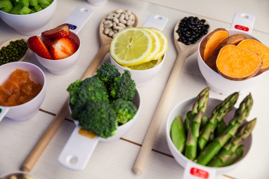 Portion cups and spoons of healthy ingredients on wooden table