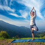 Woman in yoga Vrikshasana tree pose outdoors