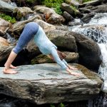 Young fit woman doing yoga oudoors at waterfall