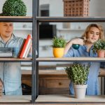 Young smiling couple at the shelf with home plants