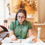 Beautiful young woman relaxing and reading a book in coffee shop