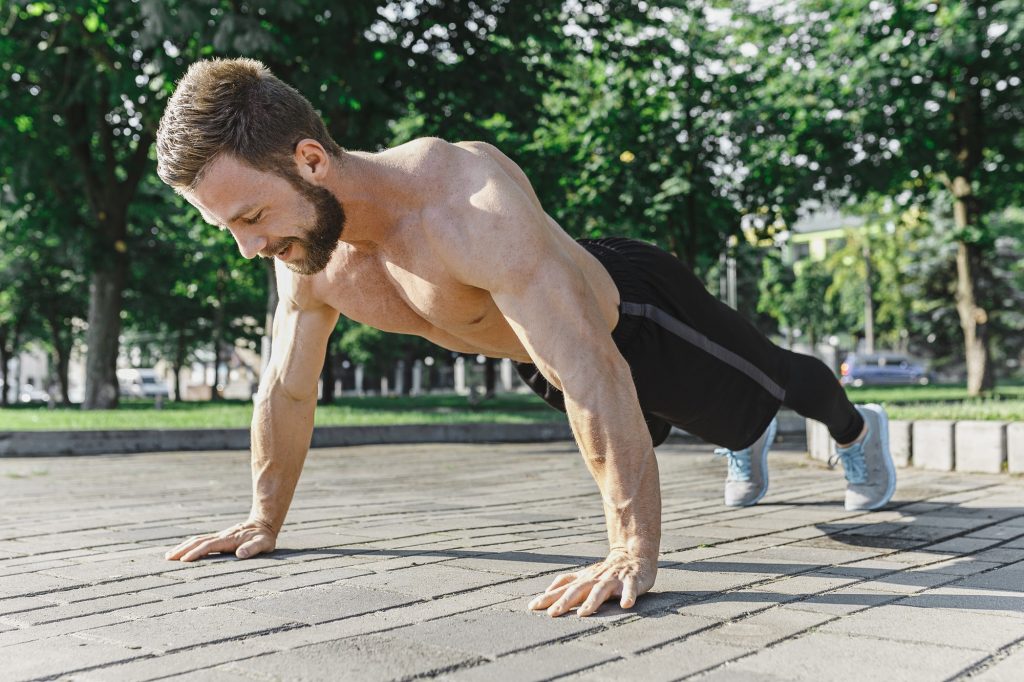 Fit fitness man doing fitness exercises outdoors at city