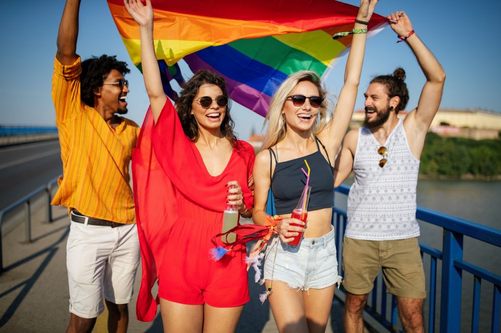 Happy group of people hanging out in the city waving LGBT with pride flag