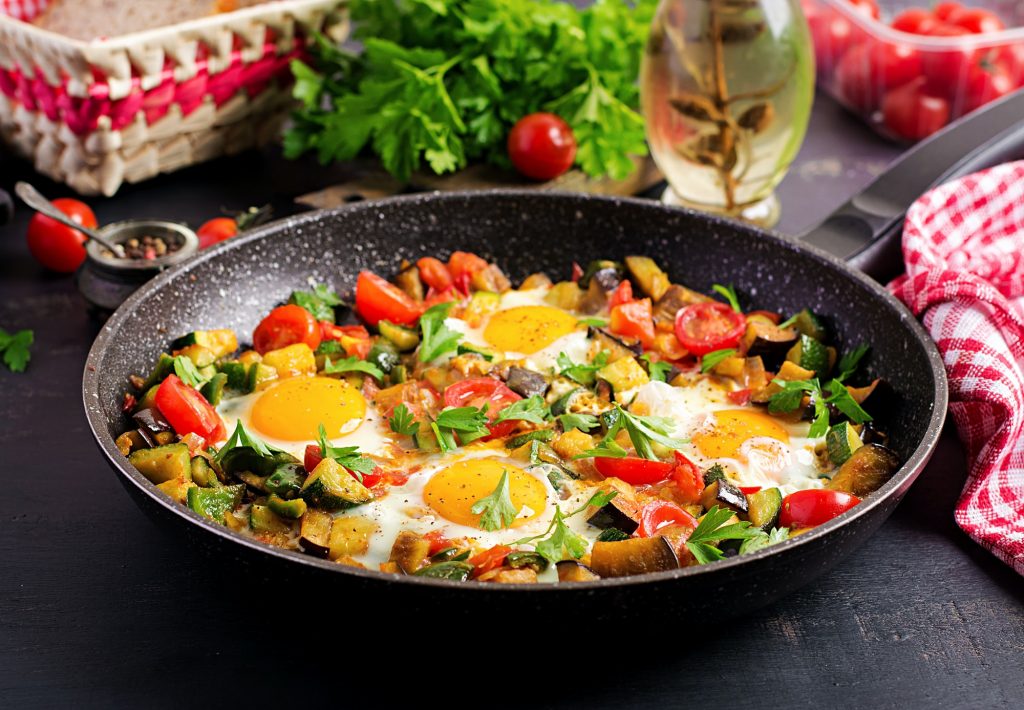 Late breakfast - fried eggs with vegetables. Shakshuka. Arabic cuisine. Kosher food.