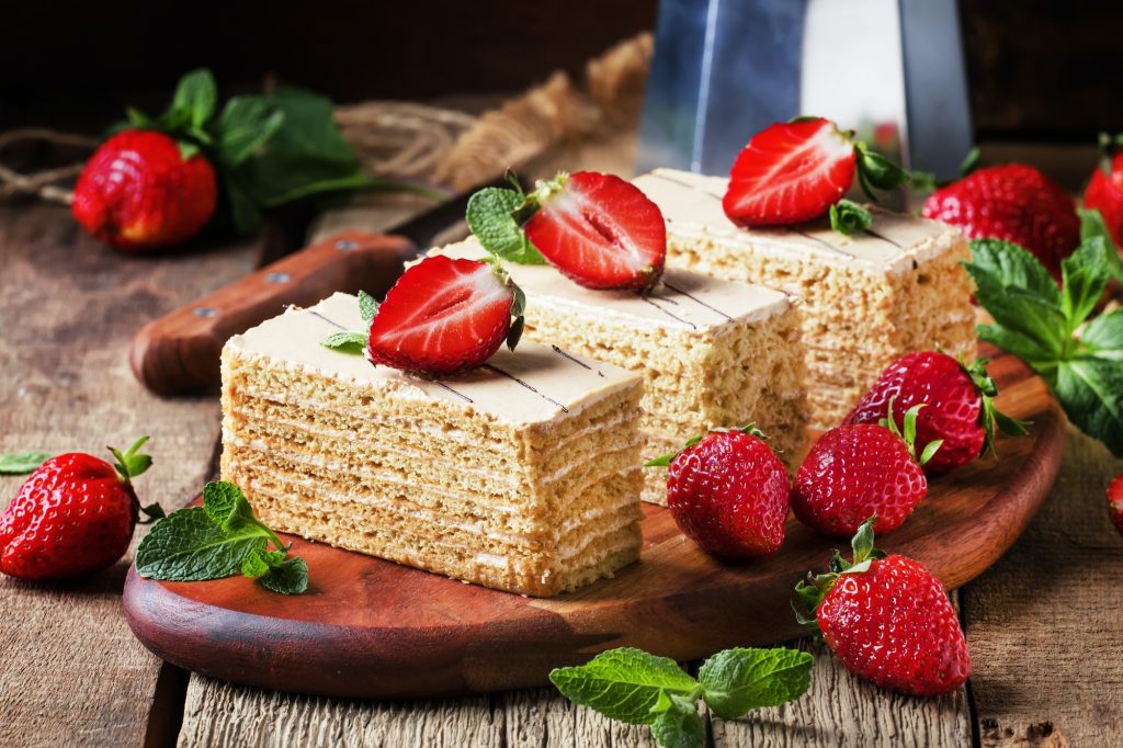 Traditional russian honey cake decorated with strawberries and green mint