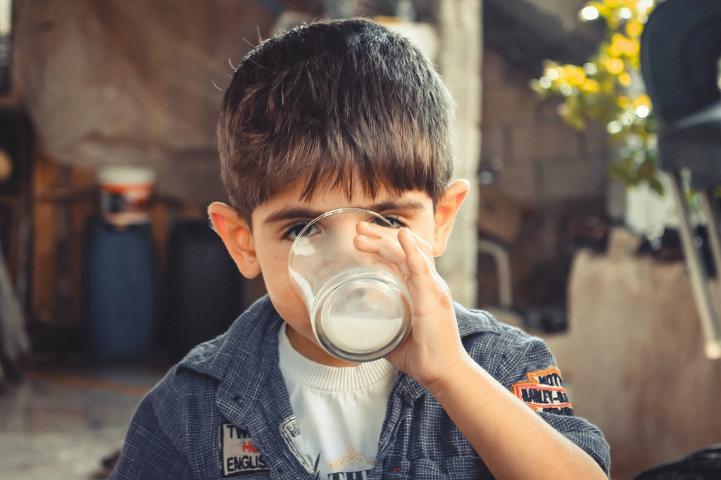 a boy gulping a glass of milk