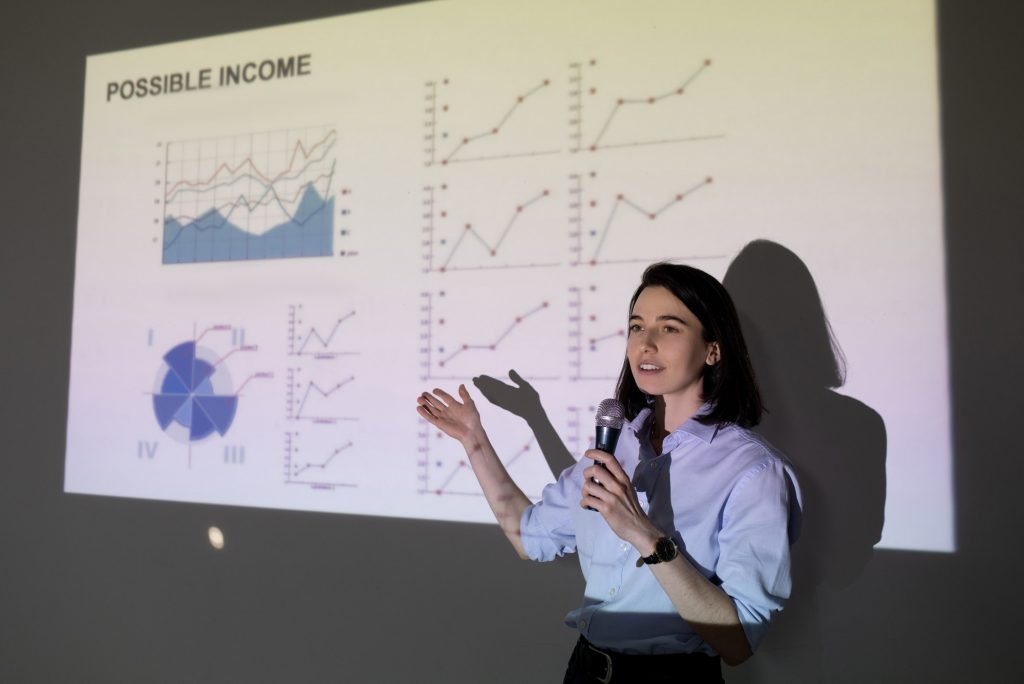 Young confident female marketer showing graph of financial development