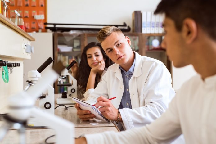 High school student with microscopes in laboratory.