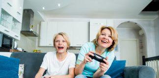 Child son and mother playing video games together at home