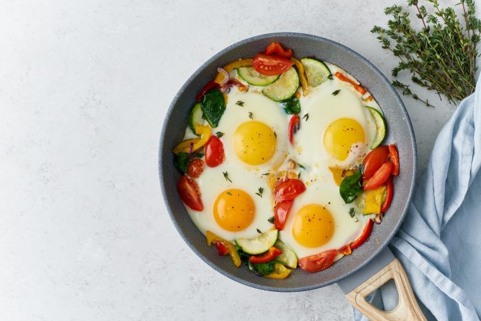 Fried eggs poached with vegetables on teflon pan, Keto meal, FODMAP recipe