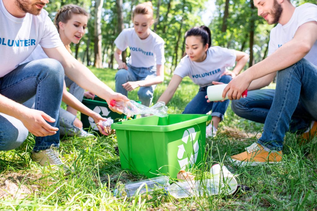 young volunteers with recycling box cleaning lawn together