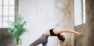 woman in gray leggings and black sports bra doing yoga on yoga mat