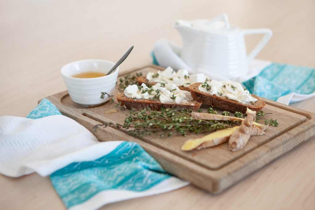 Breakfast setting sandwiches with butter, thyme, ginger and tea with honey