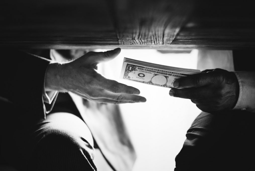 Hands passing money under the table corruption and bribery