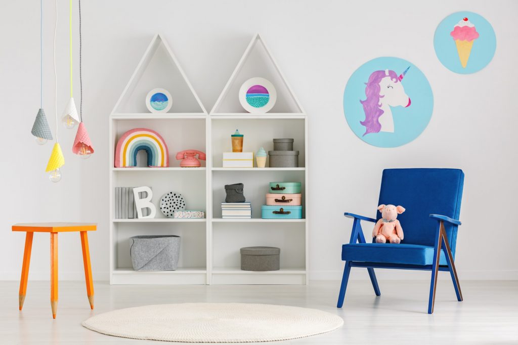 Plush toy on a blue armchair and colorful pendant lamps above an