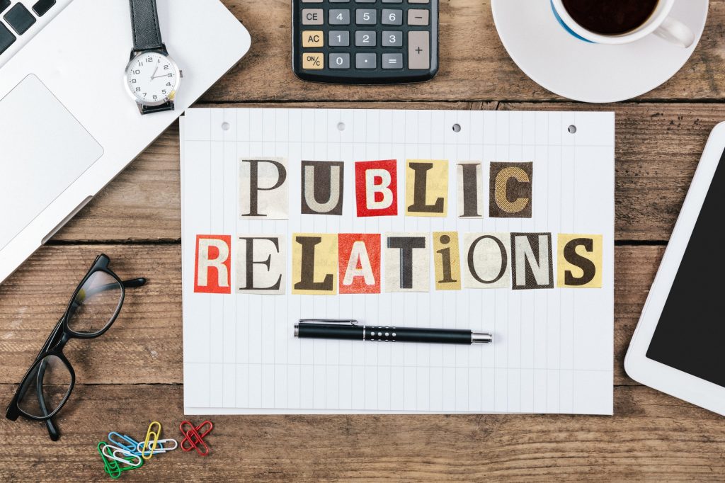 Public Relations title from newspaper cutout letters on paper notepad