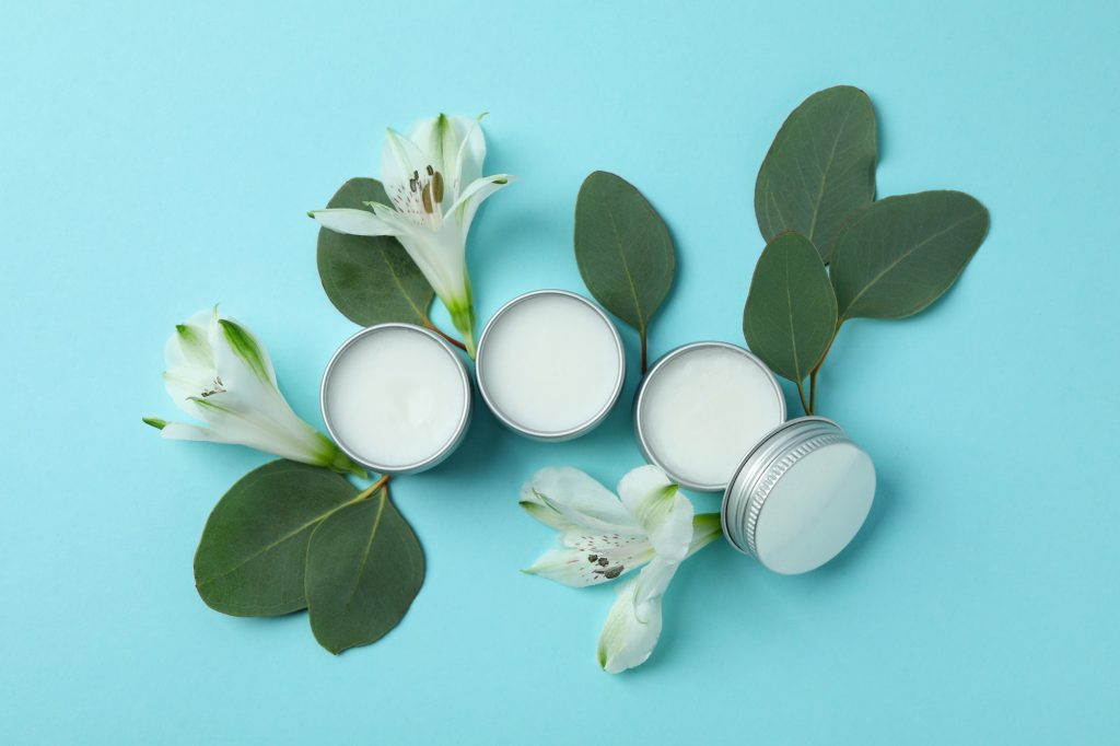 Eco lip balm and flowers on blue background