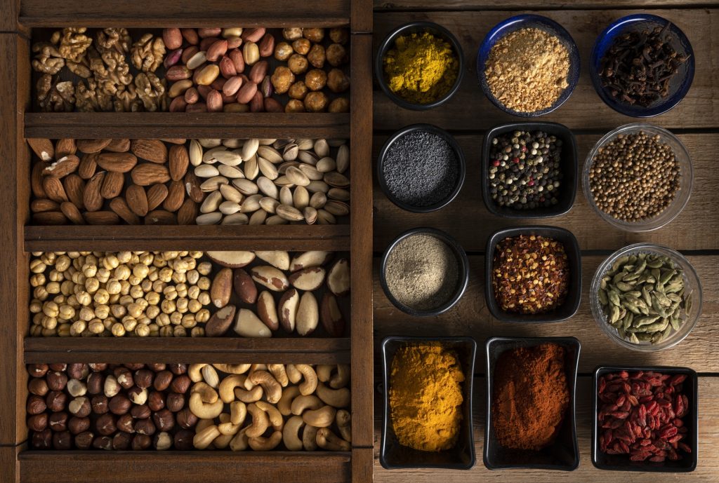 Mix of nuts in a wooden box and spices in bowls