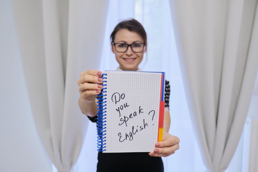 Woman English teacher holding notepad in hand with text do you speak english