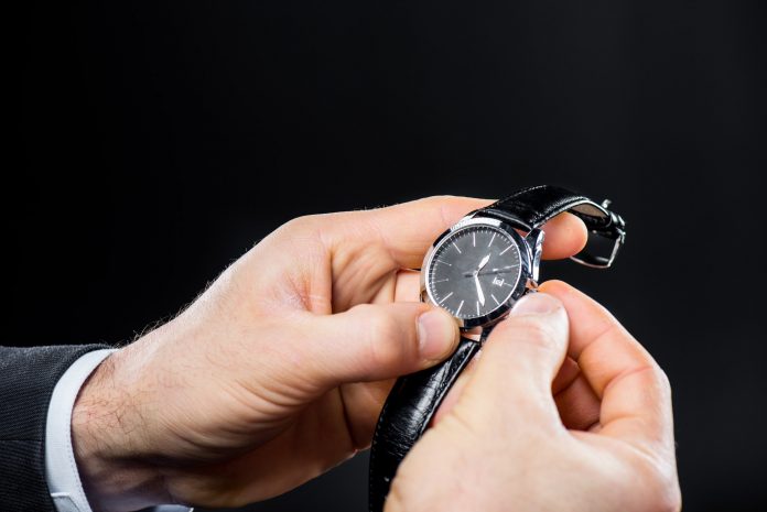 Close-up partial view of man dailing his handwatch isolated on black