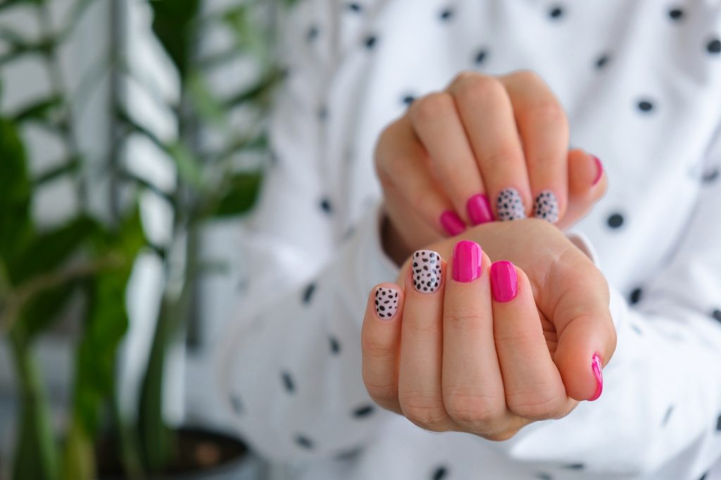 Manicured female hands with stylish pink nails and design. Trendy modern design manicure. Gel nails.