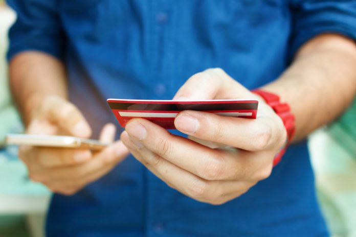 Close up man holding credit card and use smart phone with shopping online. Online payment concept.