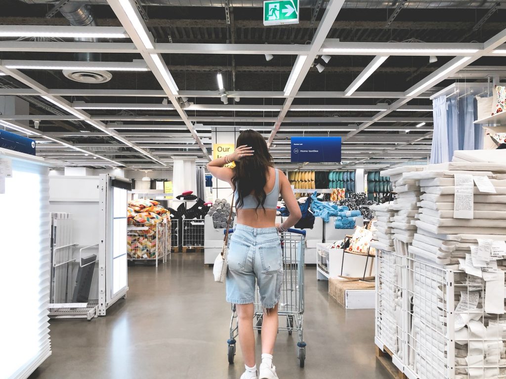 Young girl from behind pushing shopping cart at IKEA retail store