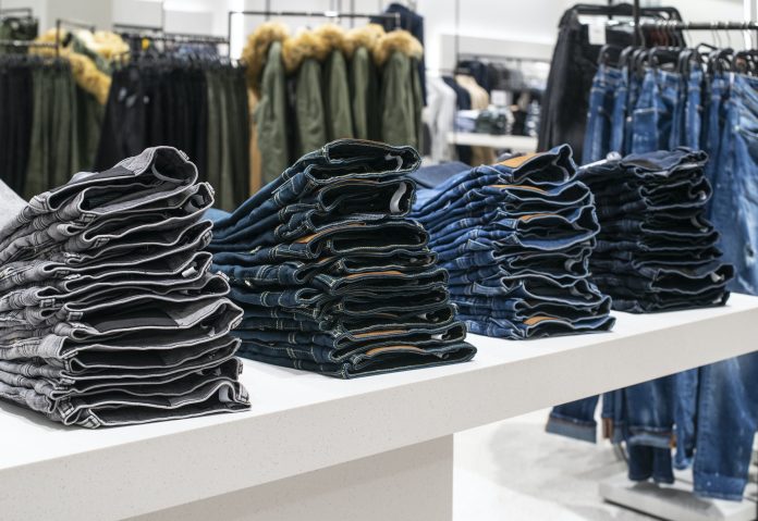 Blouses and jeans on shelf in fashion clothing store. Casual clo