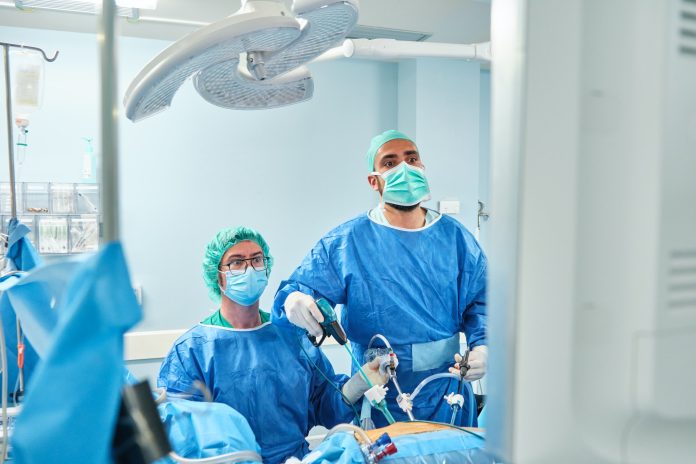 two surgeons in a laparoscopic surgical procedure look at the monitor screen