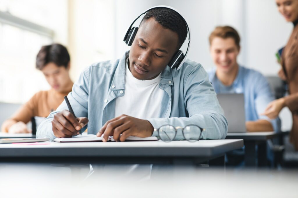 Black man sitting at desk in classroom writing exam