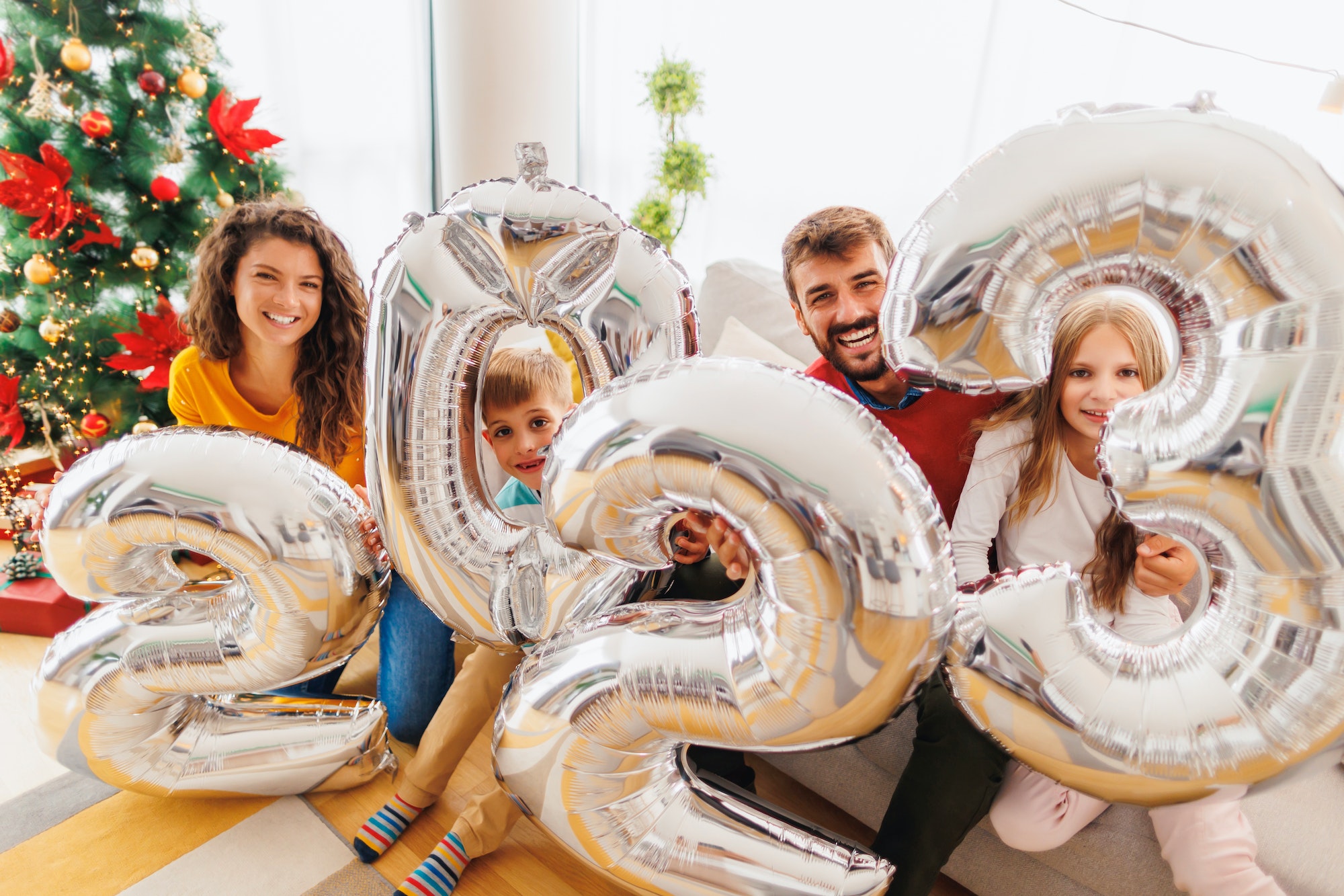 Family holding giant balloons shaped as numbers 2023 representing the upcoming New Year