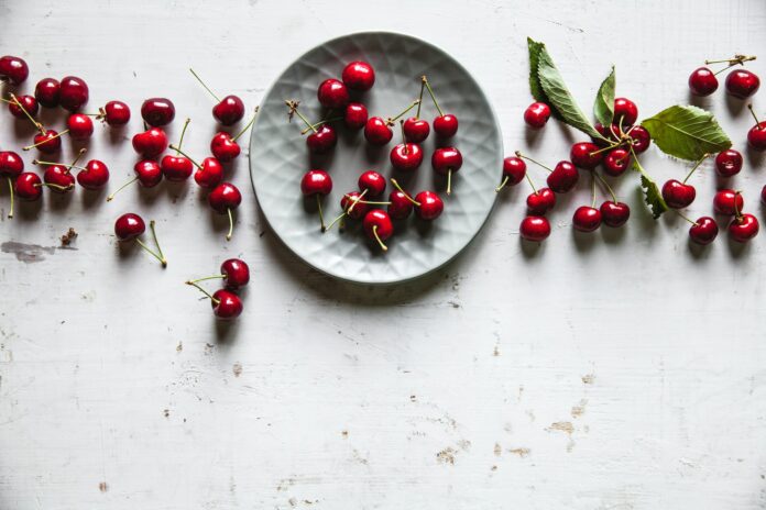 sweet cherries in a plate on an old white background, healthy food, fruits