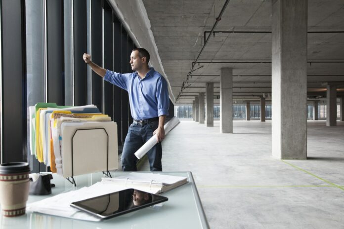 A Caucasian man at his temporary desk, in a new raw business space.