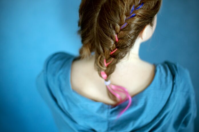 Teenager girl hairstyle on blue background. Colorful hair. Gen Z styles and trends. View from behind