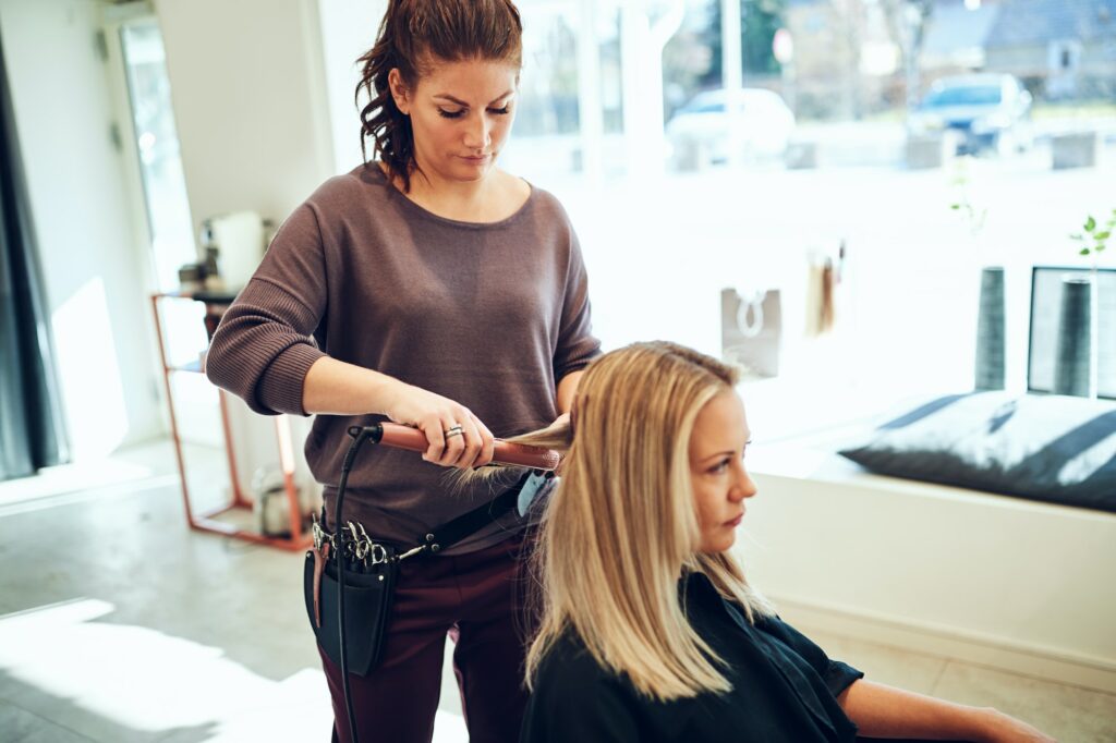 Young woman having her hair straightened by a hairdresser