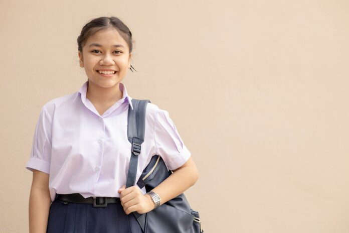 Asian School girl teen cute student in uniform happy smile with bag looking camera with space