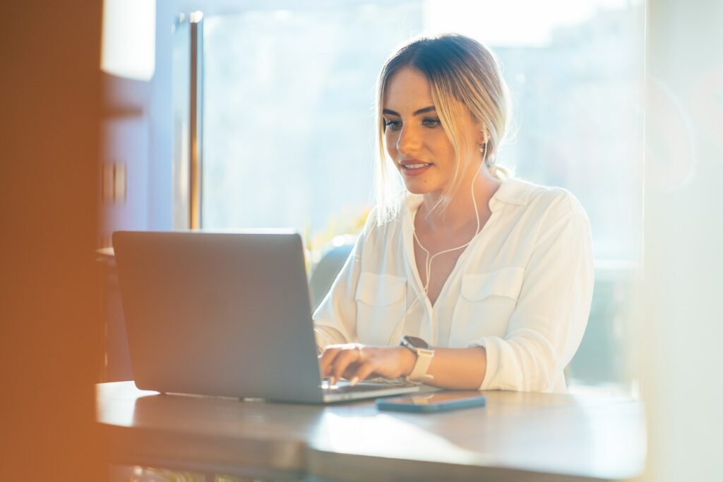 Content businesswoman typing on laptop in cafe