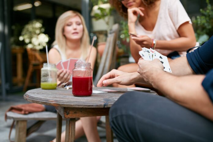 Friends sitting at outdoor cafe playing card game