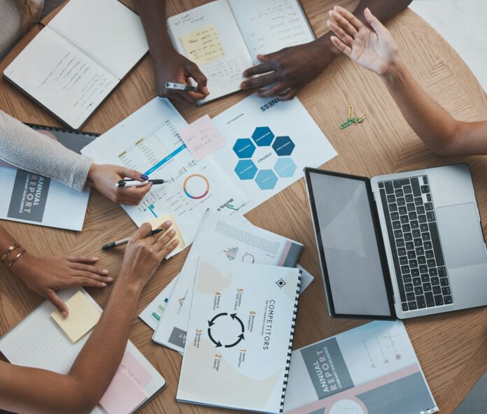 Marketing teamwork people at desk, documents of analytics strategy and top view of group working to