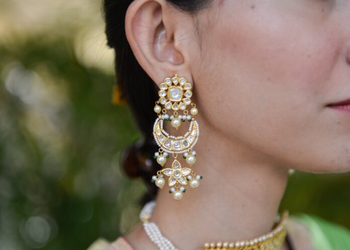 a person wearing gold and white earrings