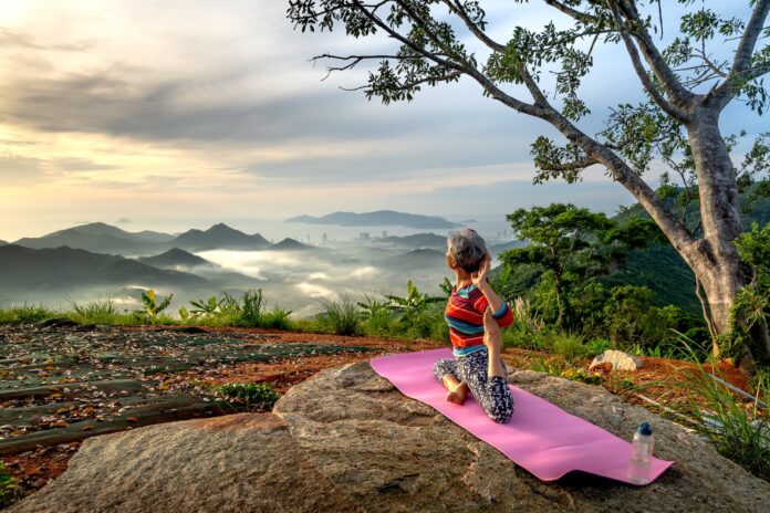 woman practising yoga on a mountain peak